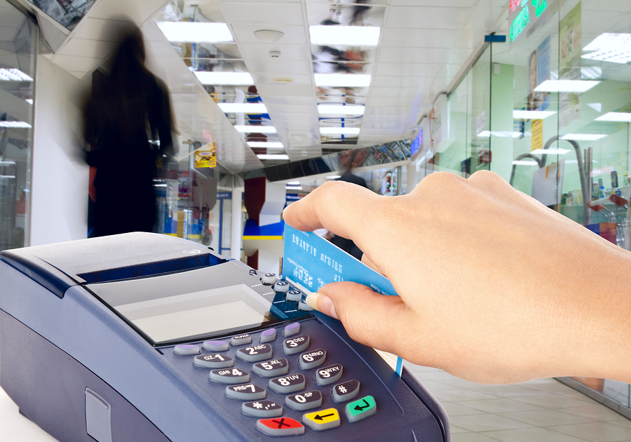 Human hand holding plastic card in payment machine in shop